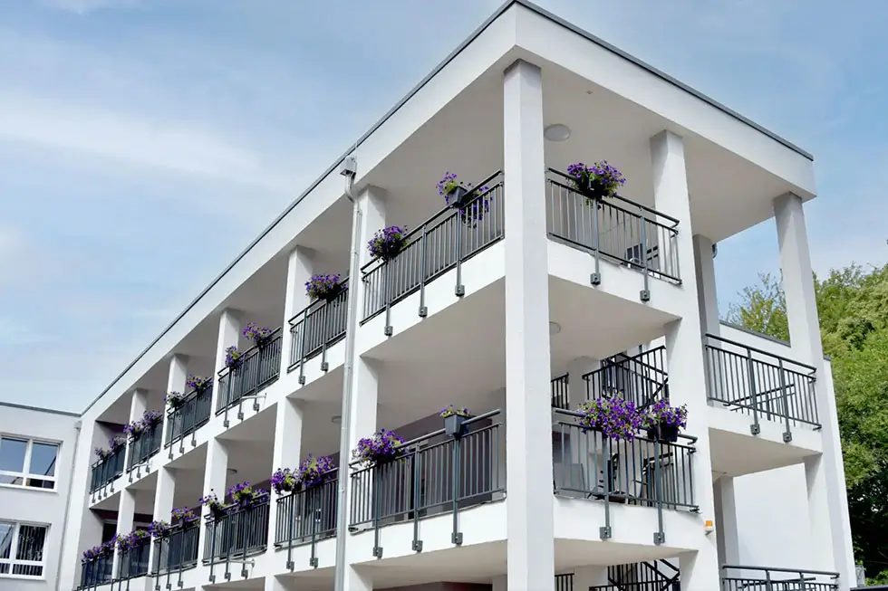 Außenansicht des Senioren- & Pflegeheims Haus Mühlberg in Krettnich mit Balkonen und Blumenkästen vor grüner Umgebung